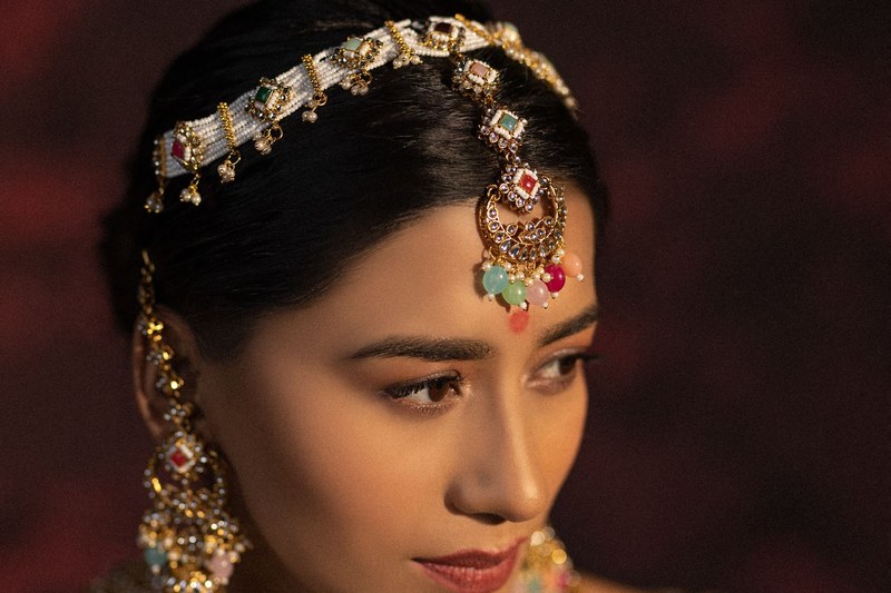 Model wearing a gold kundan matha patti and jhumka earrings in a bridal jewellery campaign shot in Jaipur