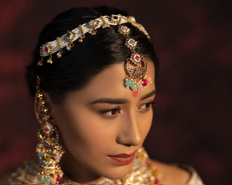 Model wearing a gold kundan matha patti and jhumka earrings in a moody bridal jewellery campaign shot in Jaipur